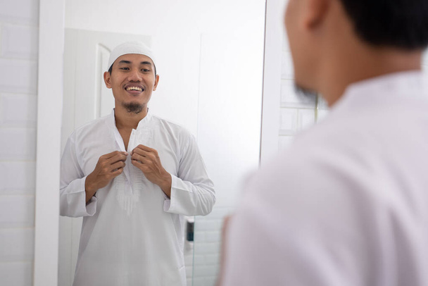 muslim man looking at mirror and get dressed before going to the mosque - 写真・画像