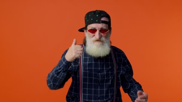 Güneş gözlüklü yaşlı ve sakallı büyükbaba el hareketini boşa harcıyor ya da etrafa para saçıyor. - Video, Çekim
