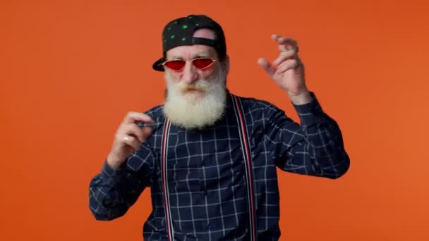 Idős szakállas nagypapa napszemüvegben zenét hallgat, zenére táncol, szórakozik - Felvétel, videó