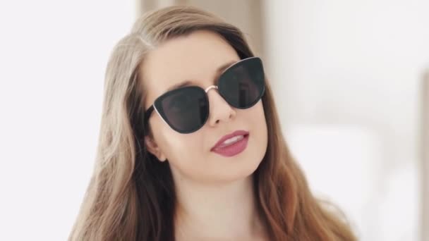 Beautiful businesswoman wearing stylish sunglasses and smiling, beauty face portrait of a caucasian european model as fashion, accessories and business people concept - Footage, Video