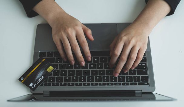Рука ділової жінки тримає кредитну картку і використовує ноутбук для онлайн-покупки та інтернет-платежів
. - Фото, зображення