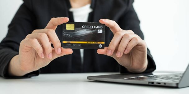 Bizneswoman 's hand trzyma kartę kredytową i używa laptopa do zakupów online i płatności internetowych. - Zdjęcie, obraz