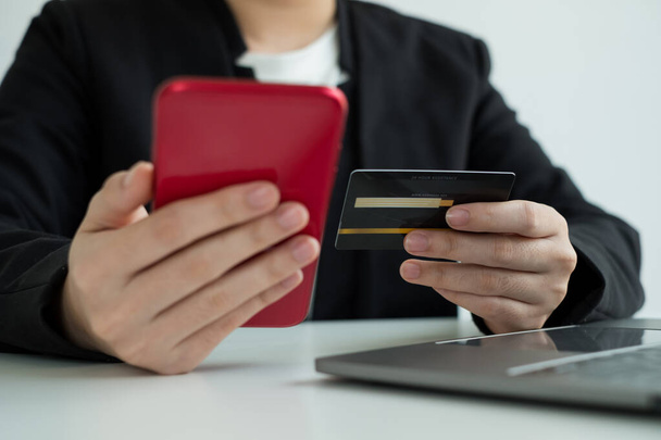 Firma trzyma w ręku kartę kredytową i używa smartfona do zakupów internetowych i płatności internetowych w biurze. - Zdjęcie, obraz