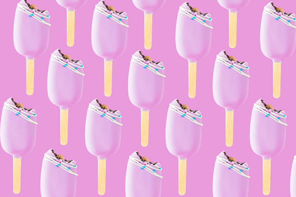 Isolated bitten pink cookie ice creams on a stick on pink background. Flat lay with icecream pattern - Photo, Image