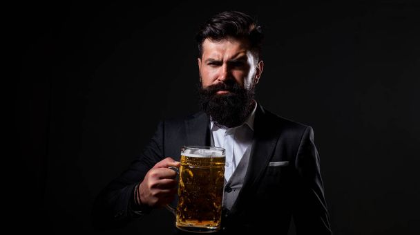 Craft beer. Confident man with glass of beer on black. Degustation and tasting. - Fotó, kép
