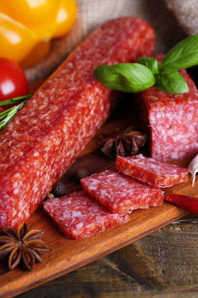Tasty salami sausage and spices on wooden background - Foto, Bild