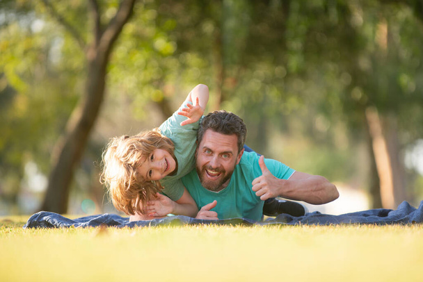 Happy father and son enjoying summer time on vacation in a sunny park. - 写真・画像