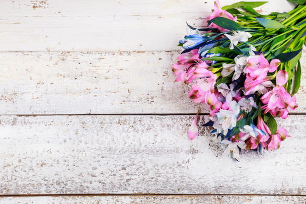 Schöner Strauß rosa und blauer Alstroemerien auf weißem Holzhintergrund. - Foto, Bild