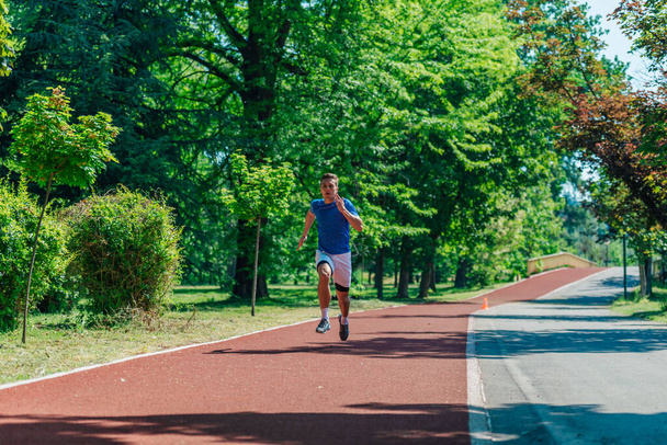 Bell'uomo che fa jogging durante la soleggiata mattinata in pista - Foto, immagini