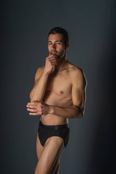 Fashion close-up portrait of a handsome male with bare torso posing in black underwear on isolated background - Fotografie, Obrázek