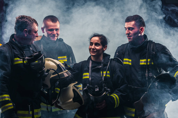 Команда пожарных, стоящая посреди дыма огнетушителя внутри пожарной части
 - Фото, изображение