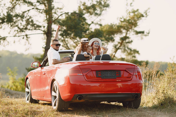 Family in a cabriolet convertible car at the sunset - Fotografie, Obrázek