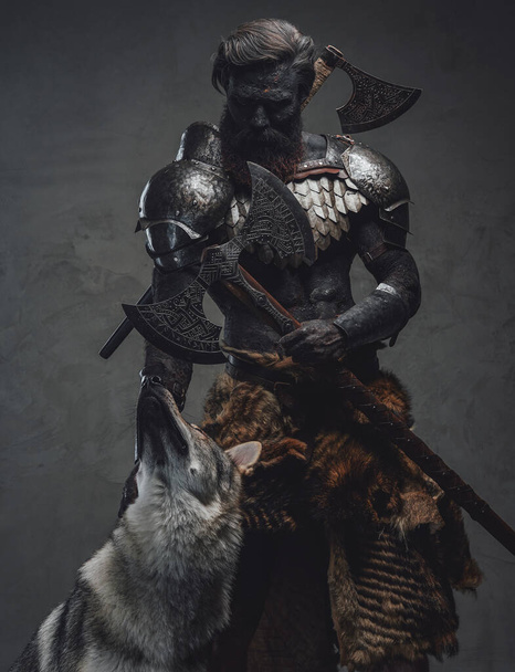 Handsome and evil guardian holding a double axe standing with a wolf - Photo, Image