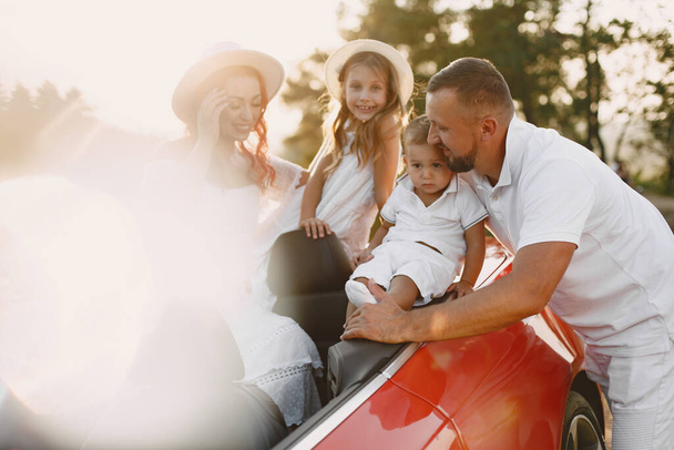 Family in a cabriolet convertible car at the sunset - 写真・画像