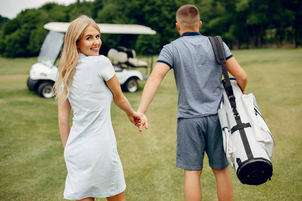 Beautiful couple playing golf on a golf course - Photo, image