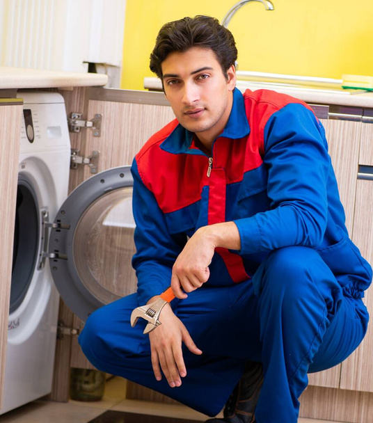 Reparador reparando lavadora en la cocina - Foto, imagen