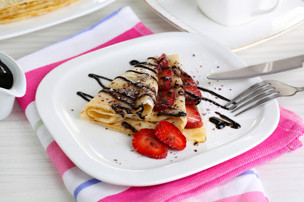 Delicious pancakes with strawberries and chocolate on plate on table - Фото, изображение