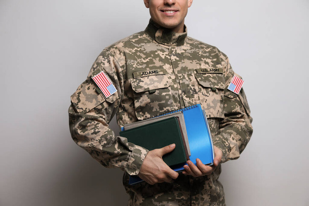 Cadet with books on grey background, closeup. Military education - Fotó, kép