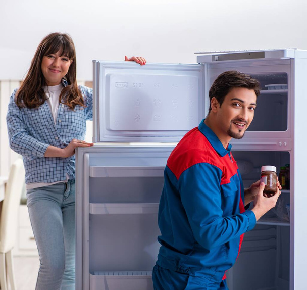 Mies korjaamassa jääkaappia asiakkaan kanssa - Valokuva, kuva