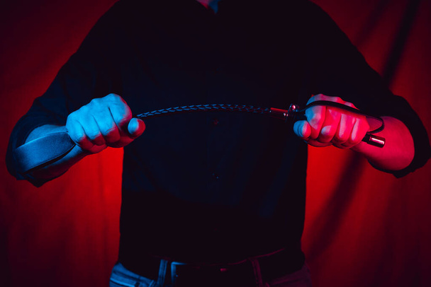 Handsome guy with a BDSM whip in his hands - Фото, изображение