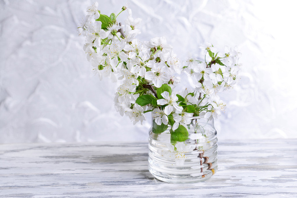 Beautiful fruit blossom in jar on table on grey background - Photo, image