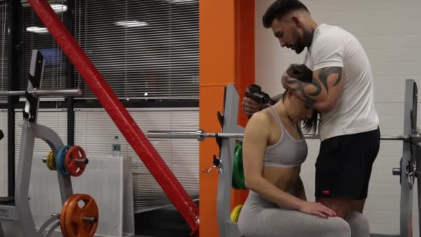 Προσωπικός γυμναστής που τεντώνει τα πόδια της αθλήτριας στο γυμναστήριο - Πλάνα, βίντεο