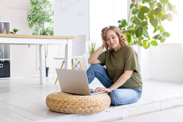 Woman using laptop computer while sitting floor at home interior. Freelance female working from home Distance learning student relaxing and watc - Photo, image