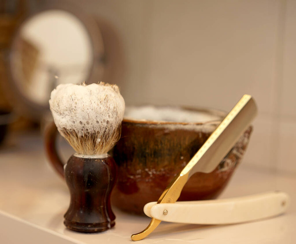 Scheermes, scheerkwast en schuimschaal in de badkamer - Foto, afbeelding