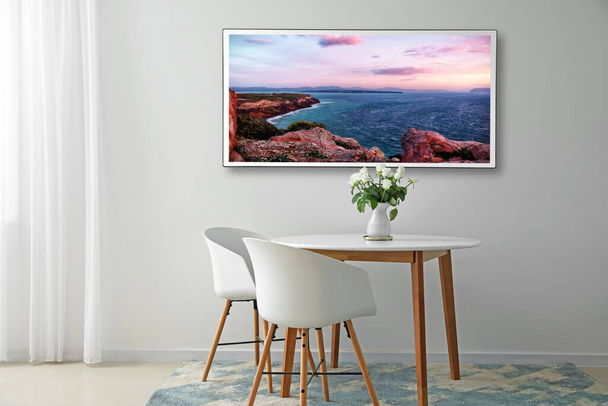 Moderner Fernseher hängt an heller Wand im Esszimmer - Foto, Bild