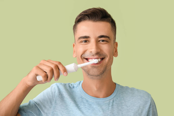 Hombre joven cepillarse los dientes en el fondo de color - Foto, imagen