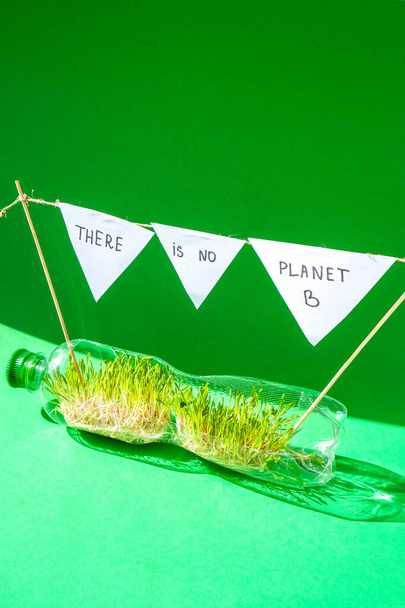 プラスチックボトルには惑星Bの若い緑の植物はありません。生態系と環境の会話。地球の日の概念。地球規模の汚染。種まき。持続可能なライフスタイル。プラスチックごみの再利用 - 写真・画像