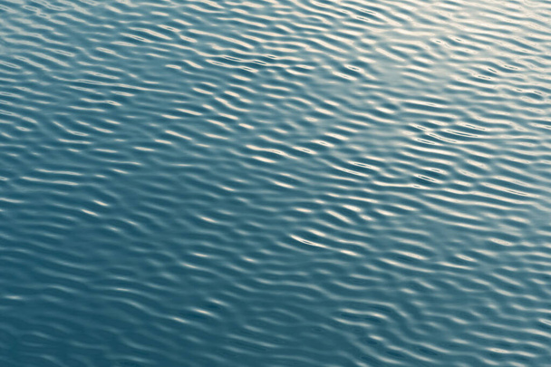 Pequeñas olas abstractas o onduladas textura de agua de fondo, lago, mar o río con puesta de sol o reflejo del amanecer  - Foto, Imagen