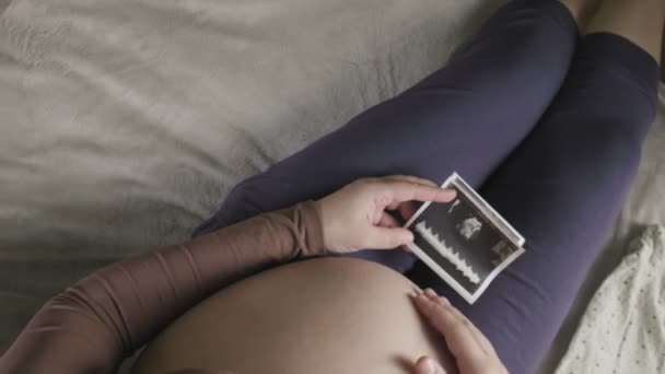 odottaa raskaana oleva nainen, jolla on suuri vatsa katsot ultraääni skannaus kotona - Materiaali, video