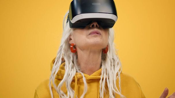 Удивительная пожилая женщина смотрит 3D-фильм в VR-очках. Старушка играет в помещении. - Фото, изображение