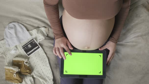 αναμένουν έγκυο γυναίκα με μεγάλη κοιλιά χρησιμοποιώντας δισκίο με chromakey στο κρεβάτι - Πλάνα, βίντεο