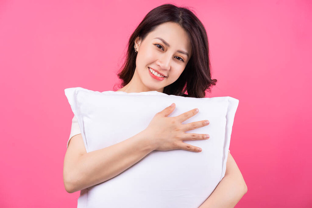 Aasialainen nainen halaa tyyny vaaleanpunainen tausta - Valokuva, kuva
