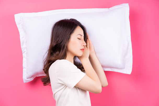 aziatische vrouw slapen op roze achtergrond - Foto, afbeelding