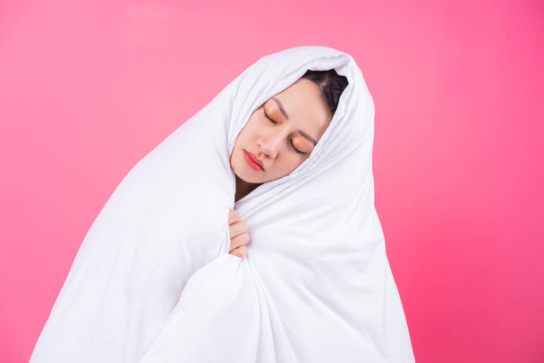 Asian woman curled up in blankets on pink background - Φωτογραφία, εικόνα