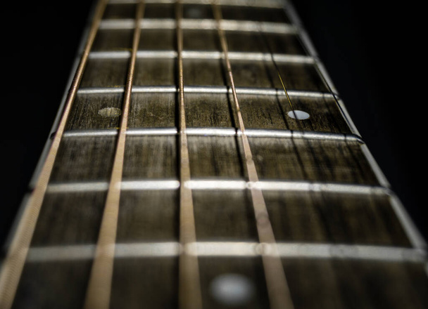 Een close-up shot van een gitaar toets met behulp van ondiepe diepte van gevijlde en zwarte achtergrond. - Foto, afbeelding