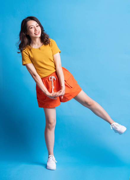 Ganzkörperfoto der schönen asiatischen Frau mit aktivem Stil auf blauem Hintergrund - Foto, Bild