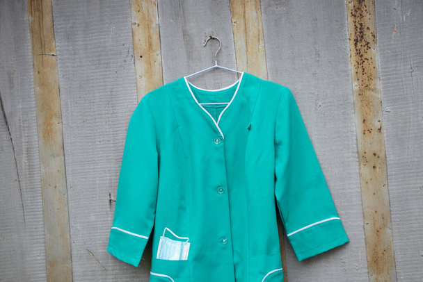 old medical suit hanging on a hanger on the wall in the street in Ukraine, nurse uniform - Photo, Image