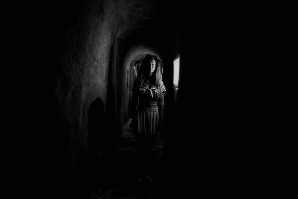Tunnel. A woman walks down a long, narrow tunnel. - Foto, imagen