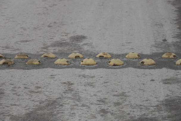 restrições de metal redondas amarelas em uma colisão de velocidade na estrada de asfalto cinza - Foto, Imagem