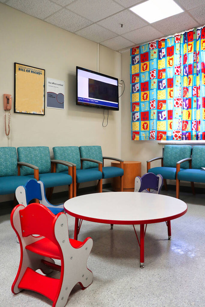 poczekalnia w klinice pediatrycznej z małym, kolorowym stołem i krzesłami oraz kolorowymi zasłonami dla zwierząt. - Zdjęcie, obraz