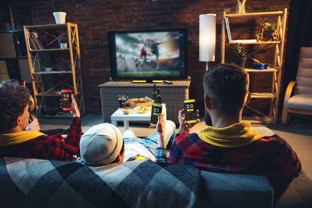 Group of friends watching TV, sport match together. Emotional fans cheering for favourite team, watching on exciting game. Concept of friendship, leisure activity, emotions - Photo, Image