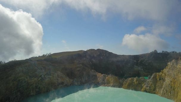 Lago del cráter Kelimutu turquesa rodeado de paredes rocosas de colores durante el día soleado. Concepto hermoso paisaje natural, isla de Ende Flores Indonesia. Disparo real de lagos multicolores - Foto, imagen