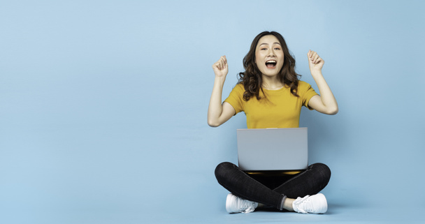 Молодая девушка сидит с ноутбуком с выражениями и жестами на заднем плане - Фото, изображение