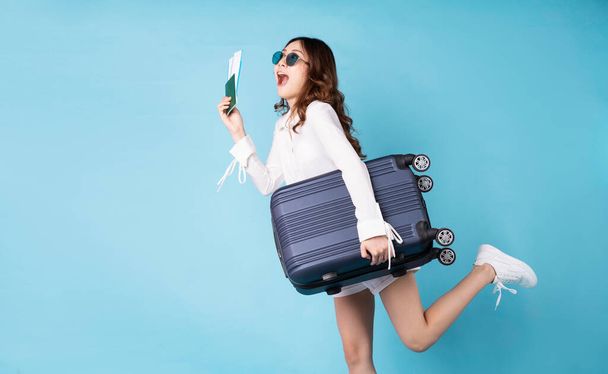 Chica joven sosteniendo el billete de avión preparándose para el próximo viaje con una expresión alegre - Foto, imagen
