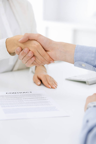 Casual dressed businessman and woman shaking hands after contract signing in white colored office. Handshake concept - Foto, Bild