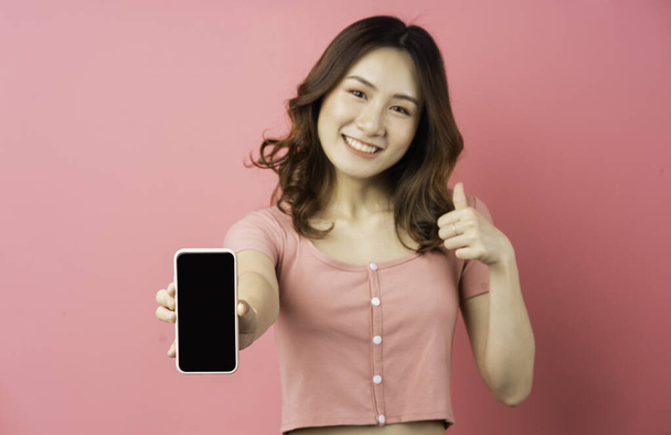 Jovem menina asiática usando o telefone no fundo rosa - Foto, Imagem